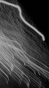 Artistic long-exposure of wavy white light streaks against a black background, creating a dynamic abstract effect.