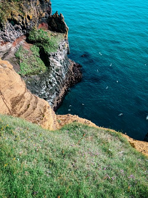 Free A breathtaking view of coastal cliffs with vibrant blue sea and lush greenery, perfect for summer adventures. Stock Photo