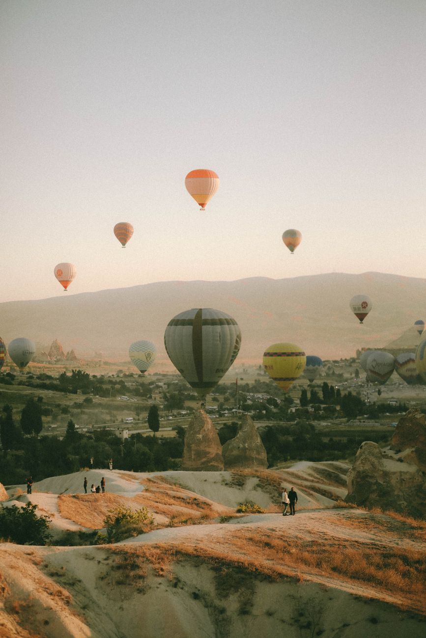 Breathtaking view of hot air balloons soaring over Cappadocia's unique landscape at sunrise.