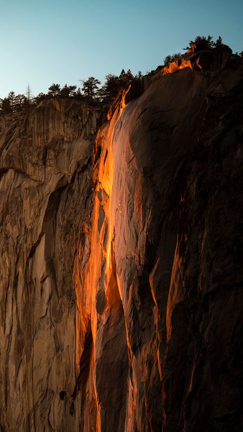 Free Sunset illuminates a dramatic rock formation, creating a fiery cascade effect. Stock Photo