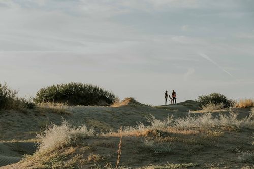 Free A serene scene of a family walking on sand dunes under a clear sky. Stock Photo