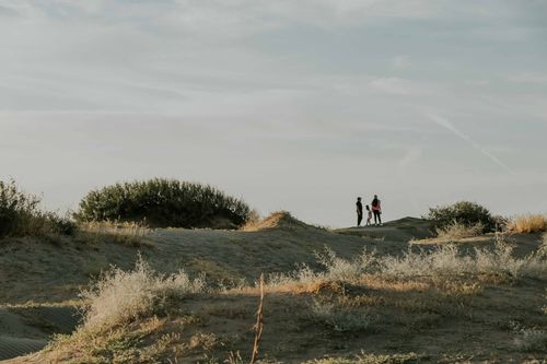 Free A family walks together on scenic desert dunes under a serene sky. Stock Photo