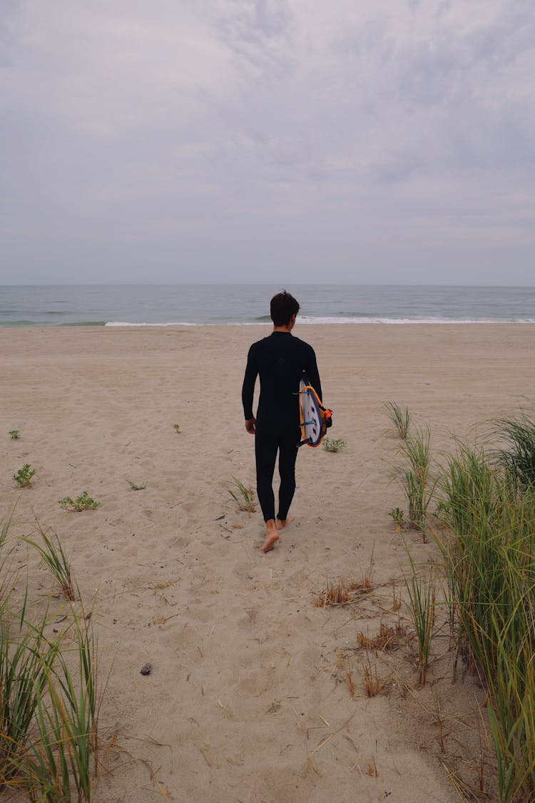 A Man Carrying A Surfboard At The Beach 