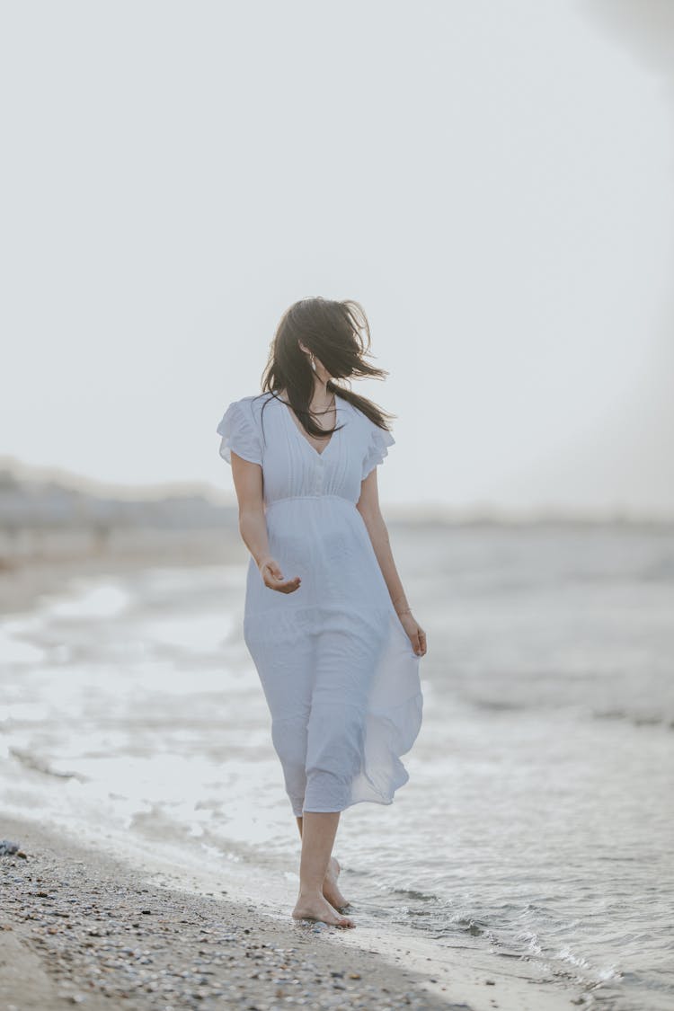 Woman In Dress Walking On Beach