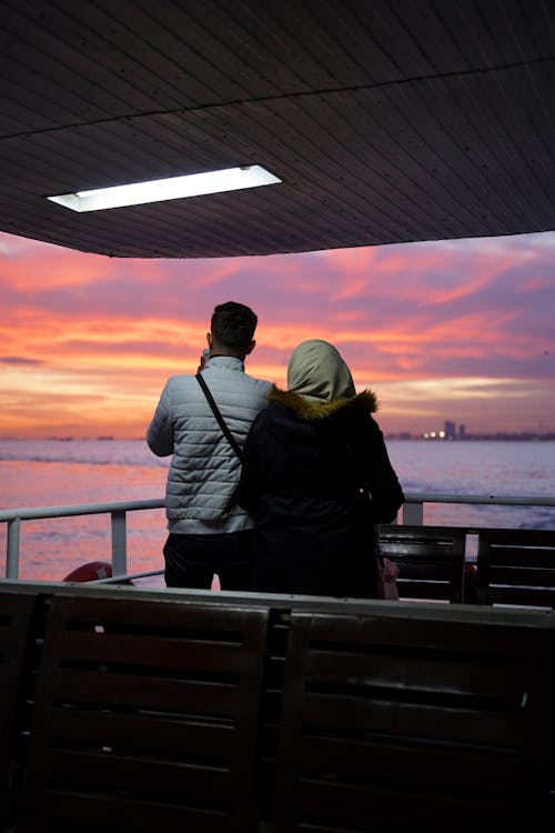 Two lovers standing on the edge of a ship at sunset