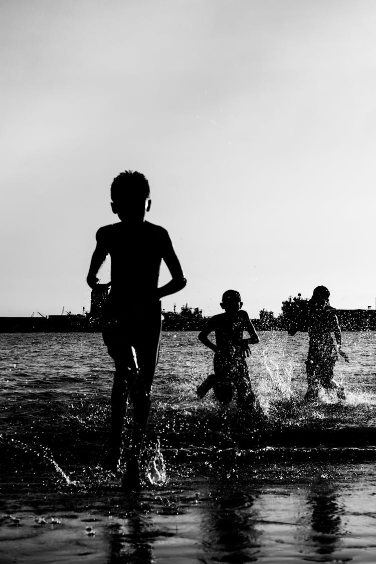 Silhouette Of Kids Running At The Beach 