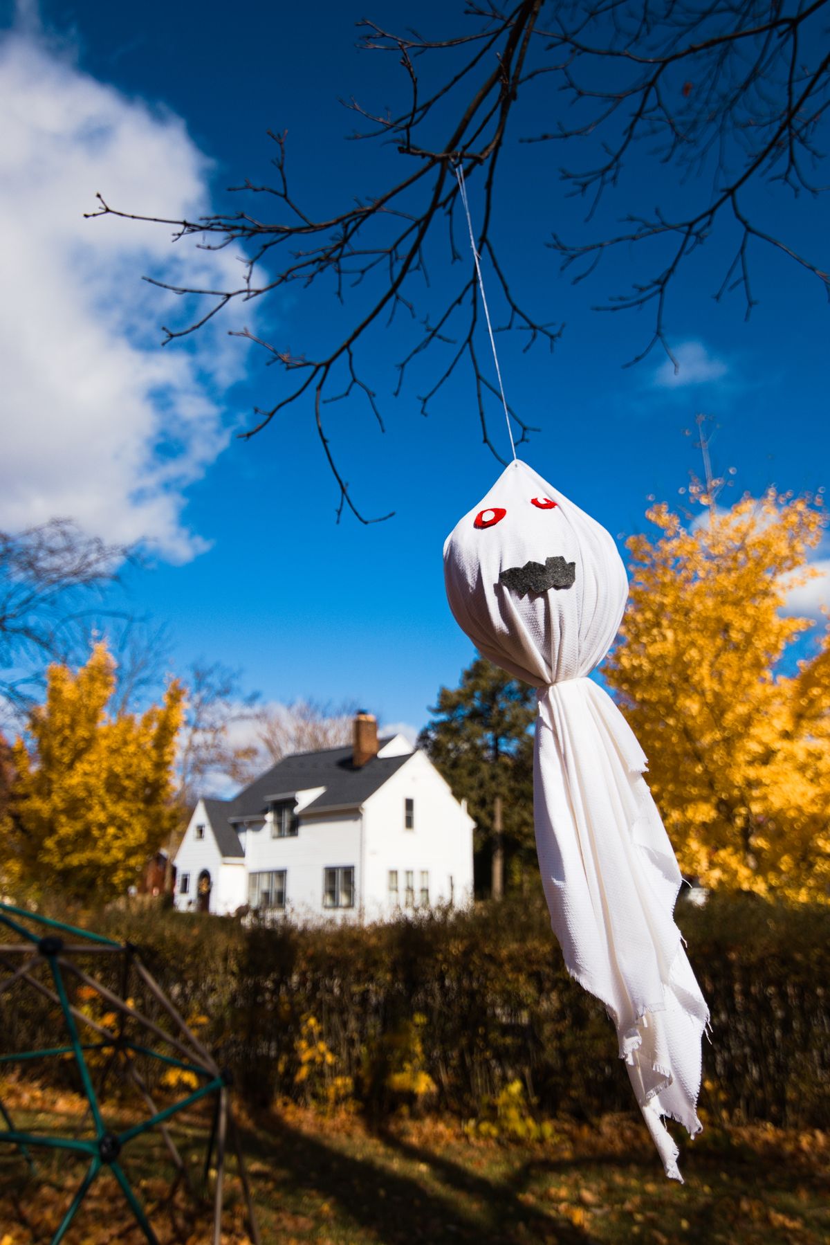 White ghost decoration hanging in front of a house for a ghostly Halloween porch