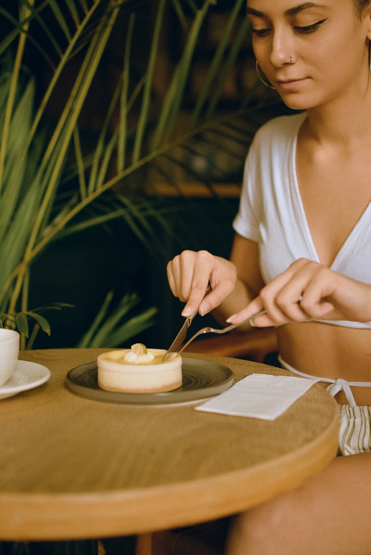 Woman Sitting At Cafe Table Eating Dessert