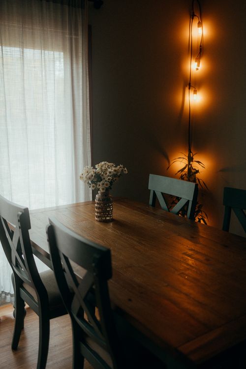 Free Warm, intimate dining area featuring a wooden table and chairs, dim lighting, and floral decor. Stock Photo