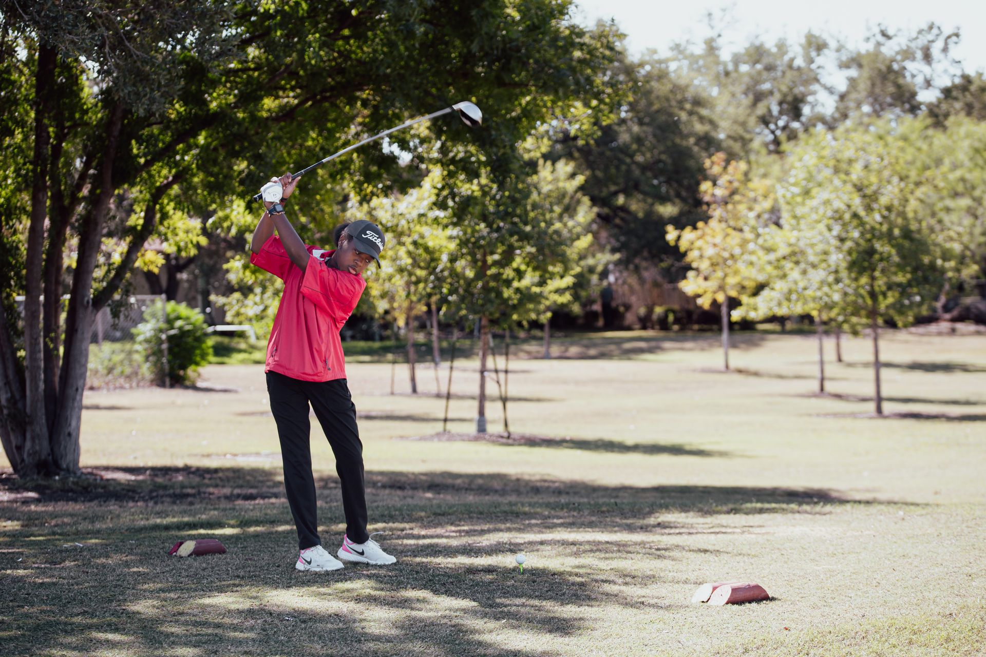 African American girl golfer swinging on a sunny day in San Antonio park.
