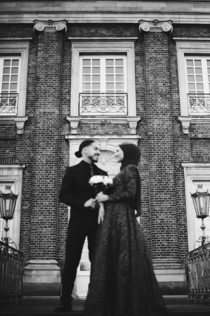 A couple standing before a brick building in Germany, captured during their wedding.