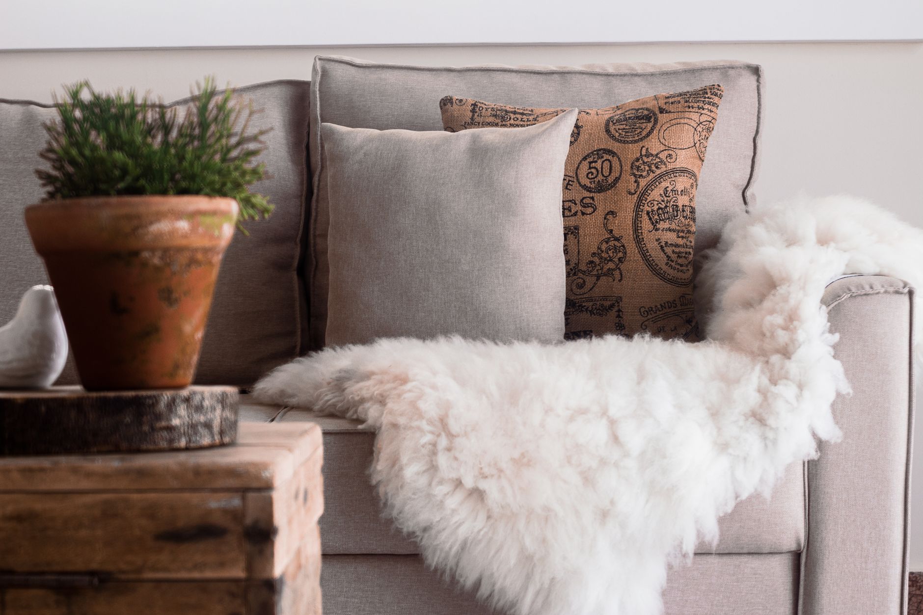 at home the home decor superstore Warm and inviting living room with a focus on soft textures, featuring a sofa with fur throws and decorative pillows.