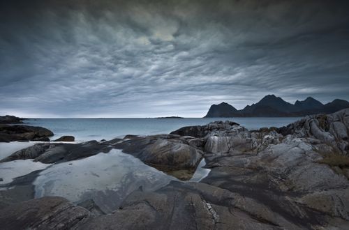 Free Moody coastal scene with rocky terrain and stormy skies in Lofoten, Norway, perfect for travel imagery. Stock Photo