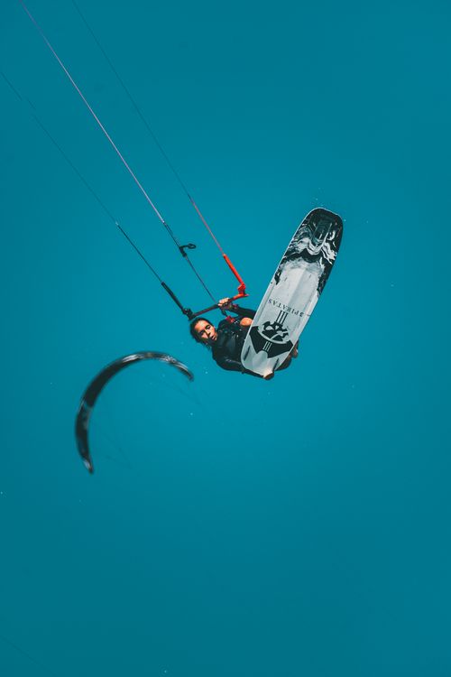 Free Woman performing an aerial kiteboarding trick, showcasing skill and agility. Stock Photo