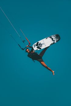 Exciting moment of a kitesurfer captured midair against a clear sky, showcasing dynamic movement and adventure.