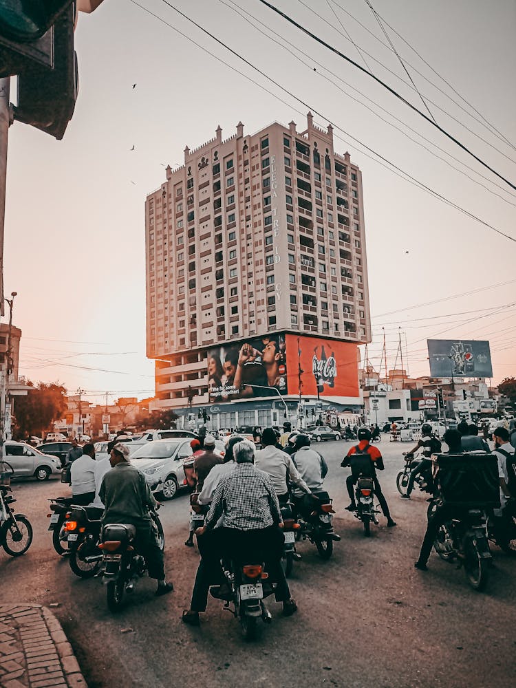 People Riding Motorcycles On The Road Near The Building