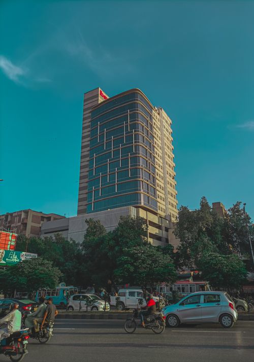 Free A modern high-rise building against a clear sky with street traffic in the foreground. Stock Photo