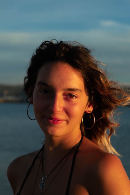 Free Close-up portrait of a woman with hoop earrings during sunset by the sea. Stock Photo