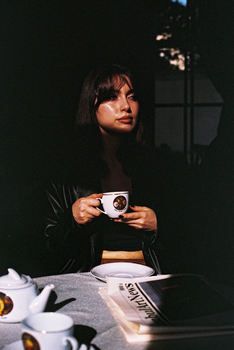 Woman Drinking Coffee At Table In Cafe