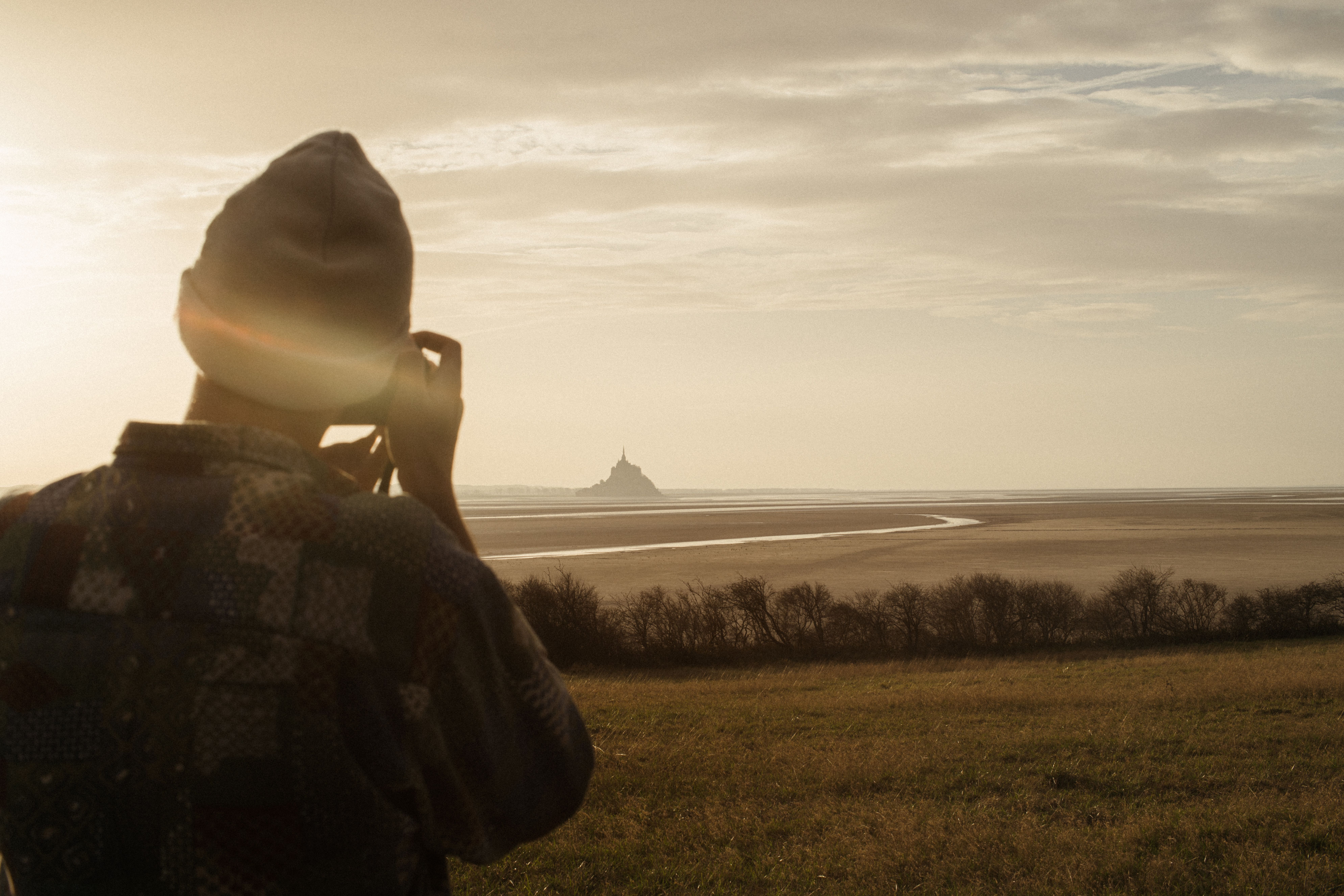 Photographer captures the stunning Mont Saint Michel landscape during sunset from the countryside.