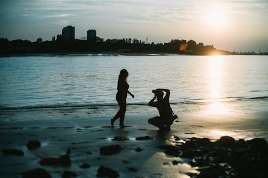 A scenic sunset beach photoshoot featuring silhouettes of a woman and a photographer.