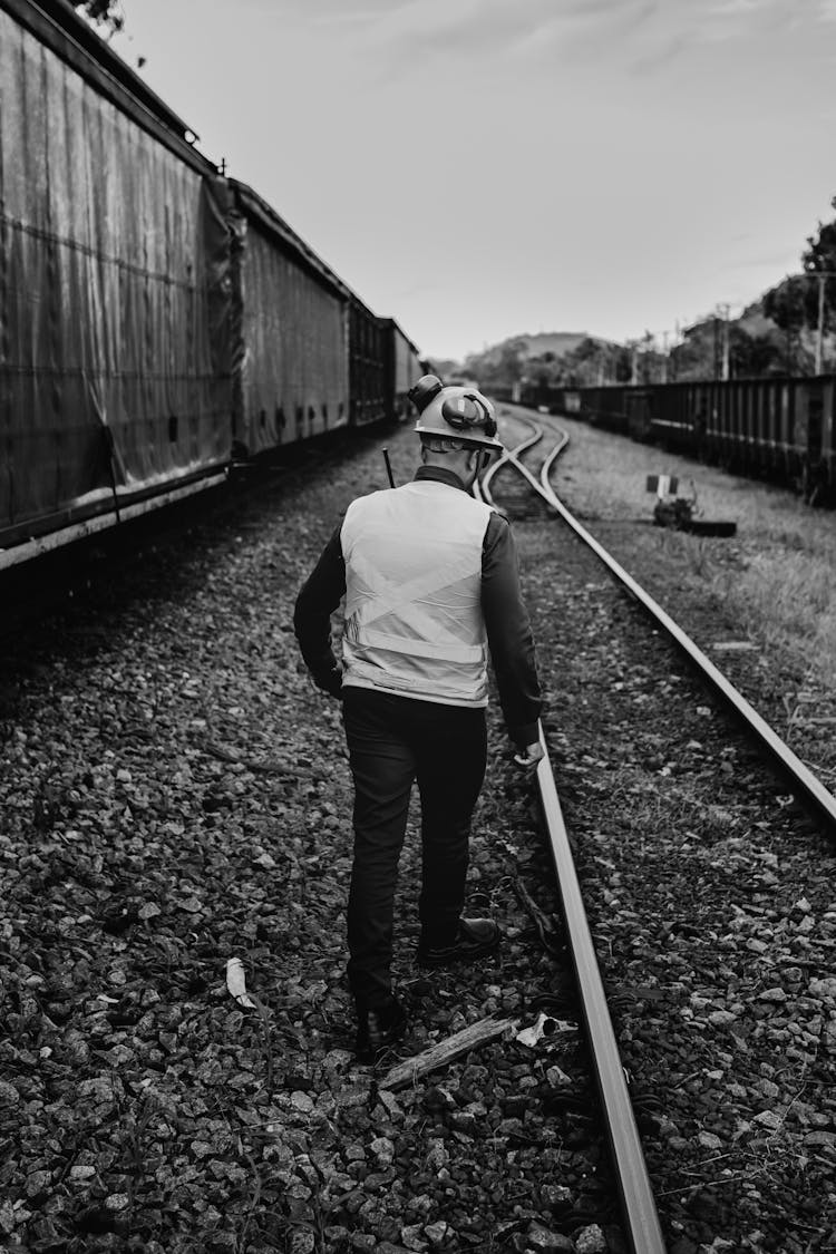 Back View Of A Railroad Worker Walking On The Train Tracks