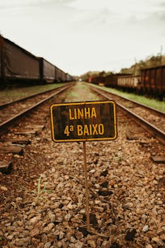 Rustic railway tracks featuring a vintage "Linha 4a Baixo" sign amidst cargo trains.