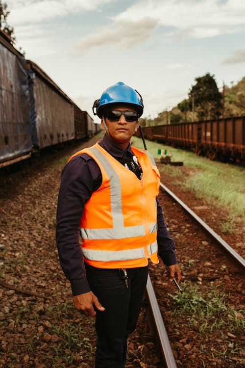 A Worker Wearing a Safety Helmet and Safety Vest while Standing on a Railway