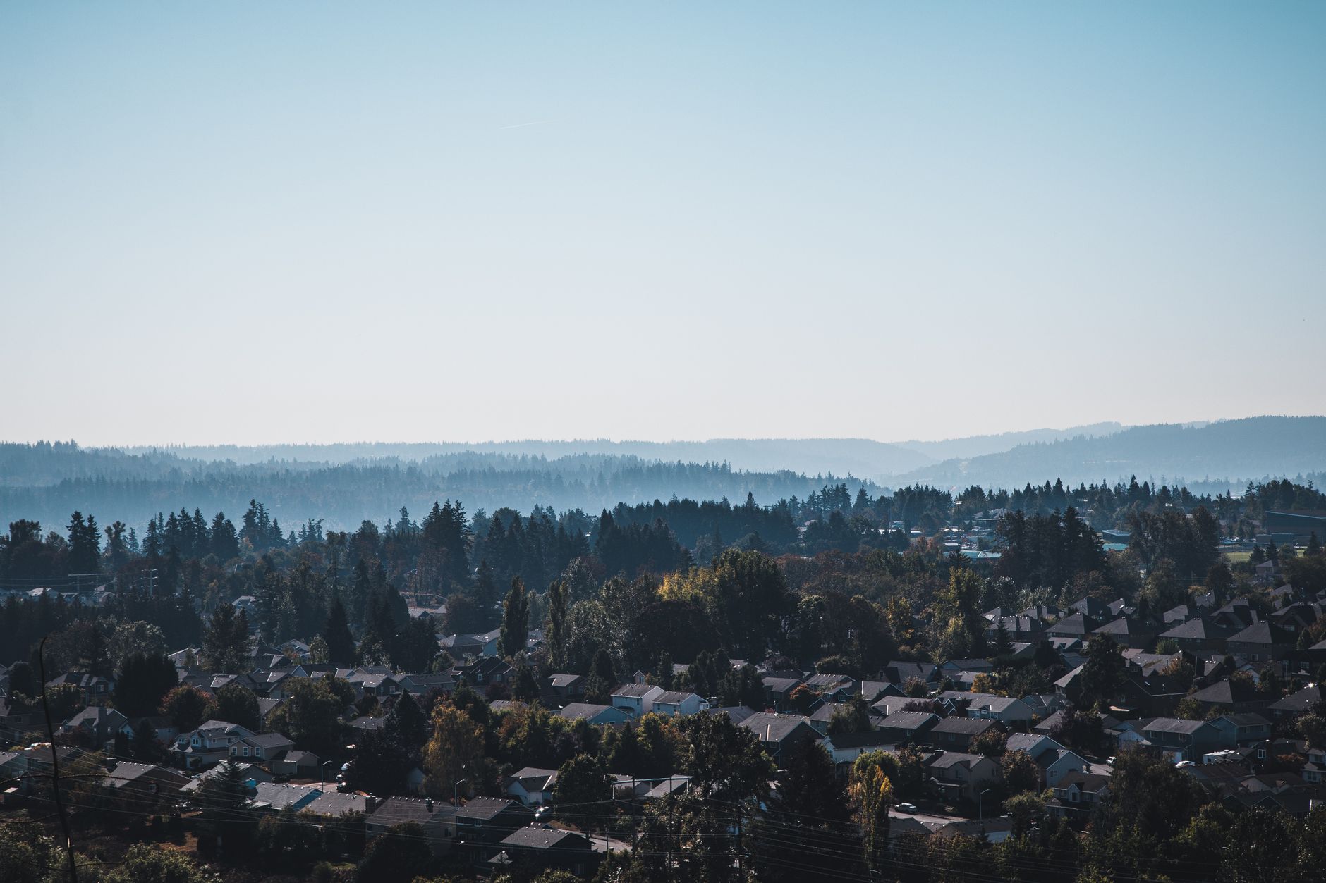 Captivating aerial view of Happy Valley suburbs against misty hills and forest backdrop.