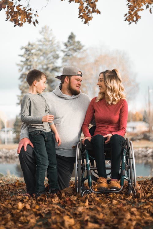 Woman Using a Wheelchair with Her Husband and Son in the Autumn Park by the River