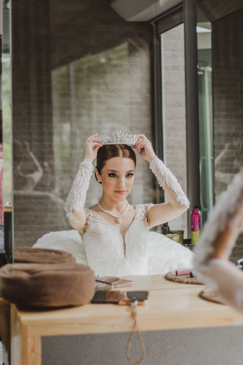 Free A bride in a lace wedding dress adjusts her tiara, preparing for her special day. Stock Photo