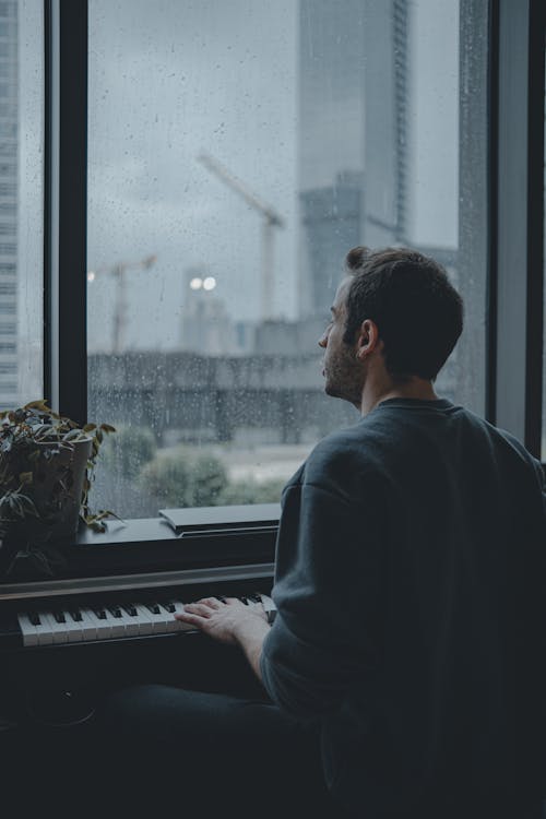 Man Playing Piano near Glass Wall