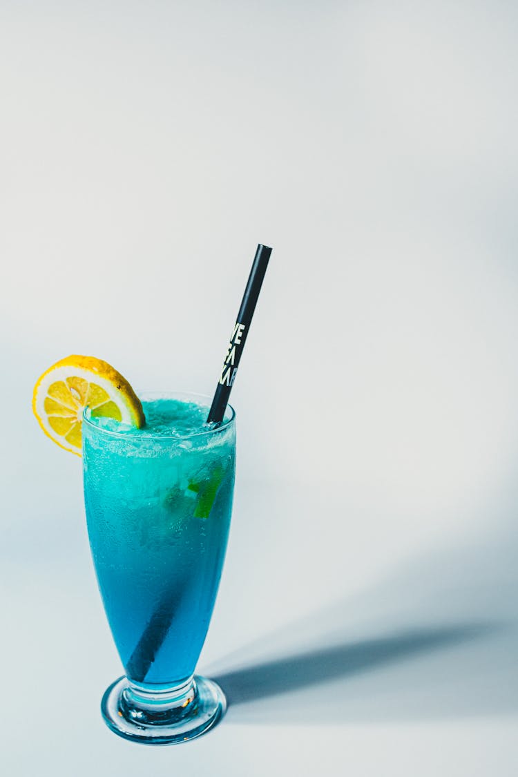 A Blue Cocktail With A Lemon Slice In A Tall Glass 