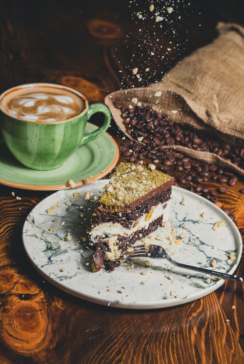 Free A tempting slice of cake with cappuccino, perfect for dessert lovers. Stock Photo