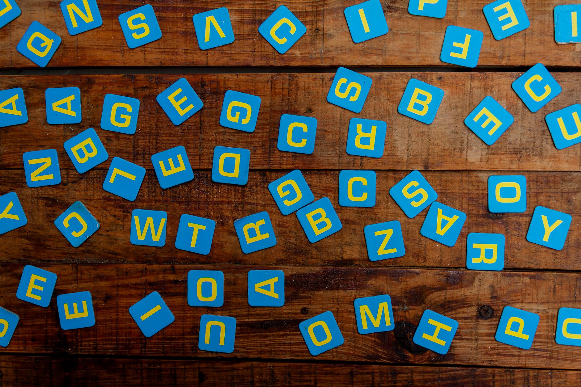 Bright blue alphabet tiles scattered on a rustic wooden table, perfect for educational themes.