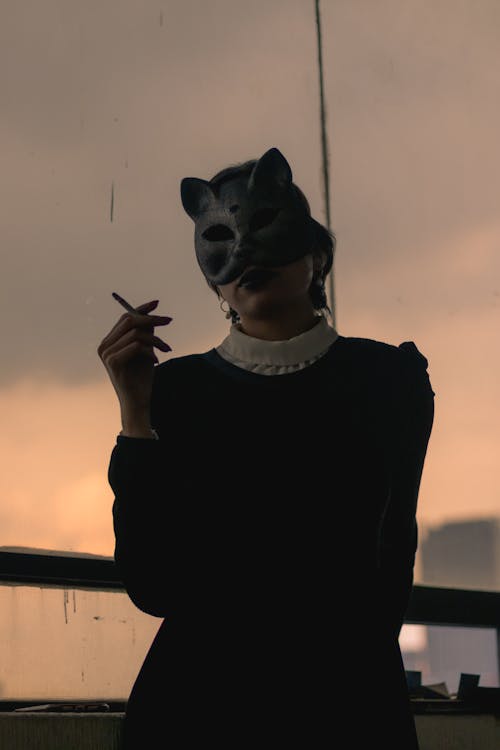 A Woman in Black Long Sleeves Wearing Cat Mask