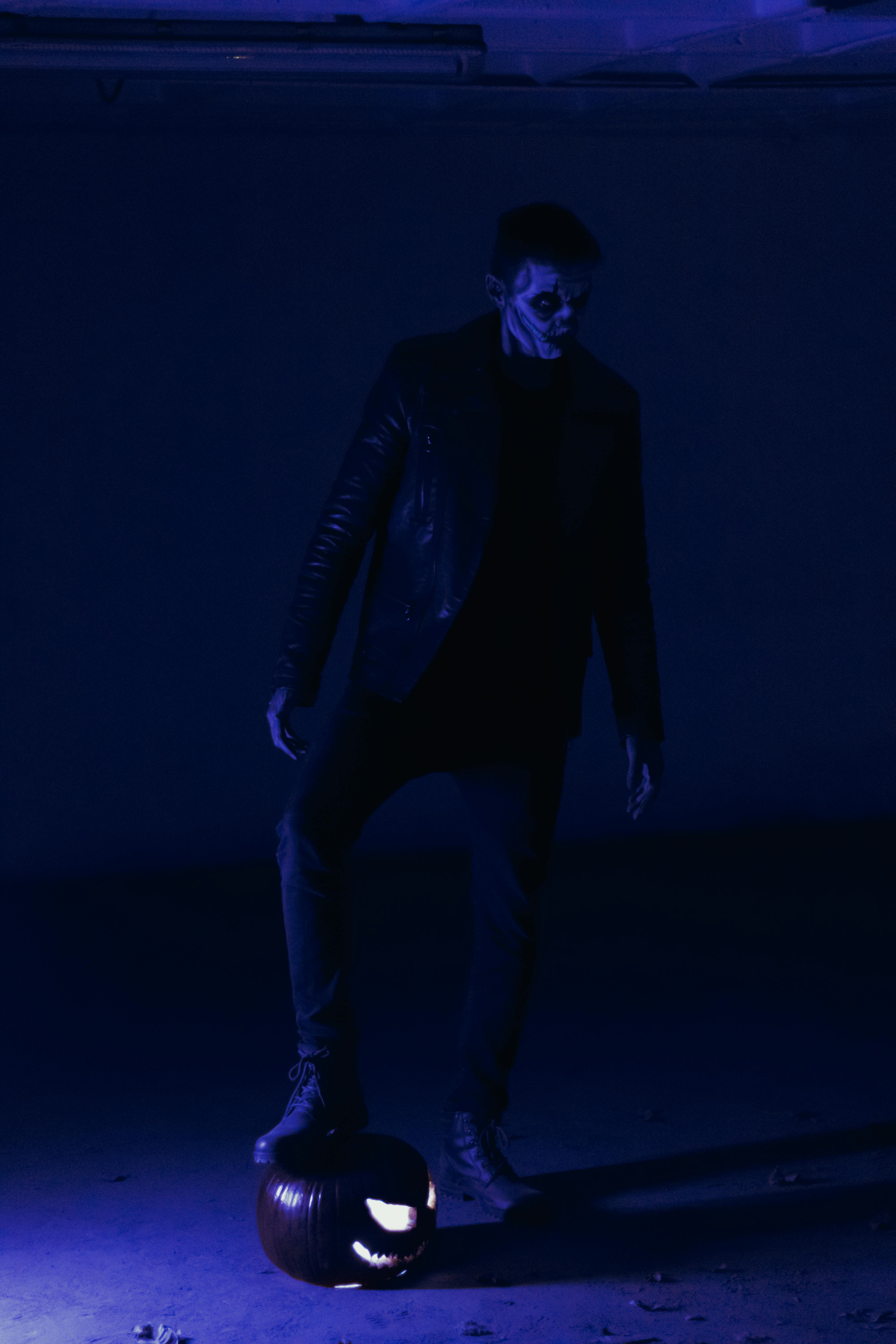 a man in black leather jacket stepping on jack o lantern