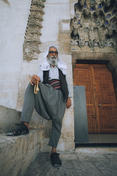Free Elderly man in traditional attire sitting outside a historic religious temple, evoking a sense of culture and spirituality. Stock Photo