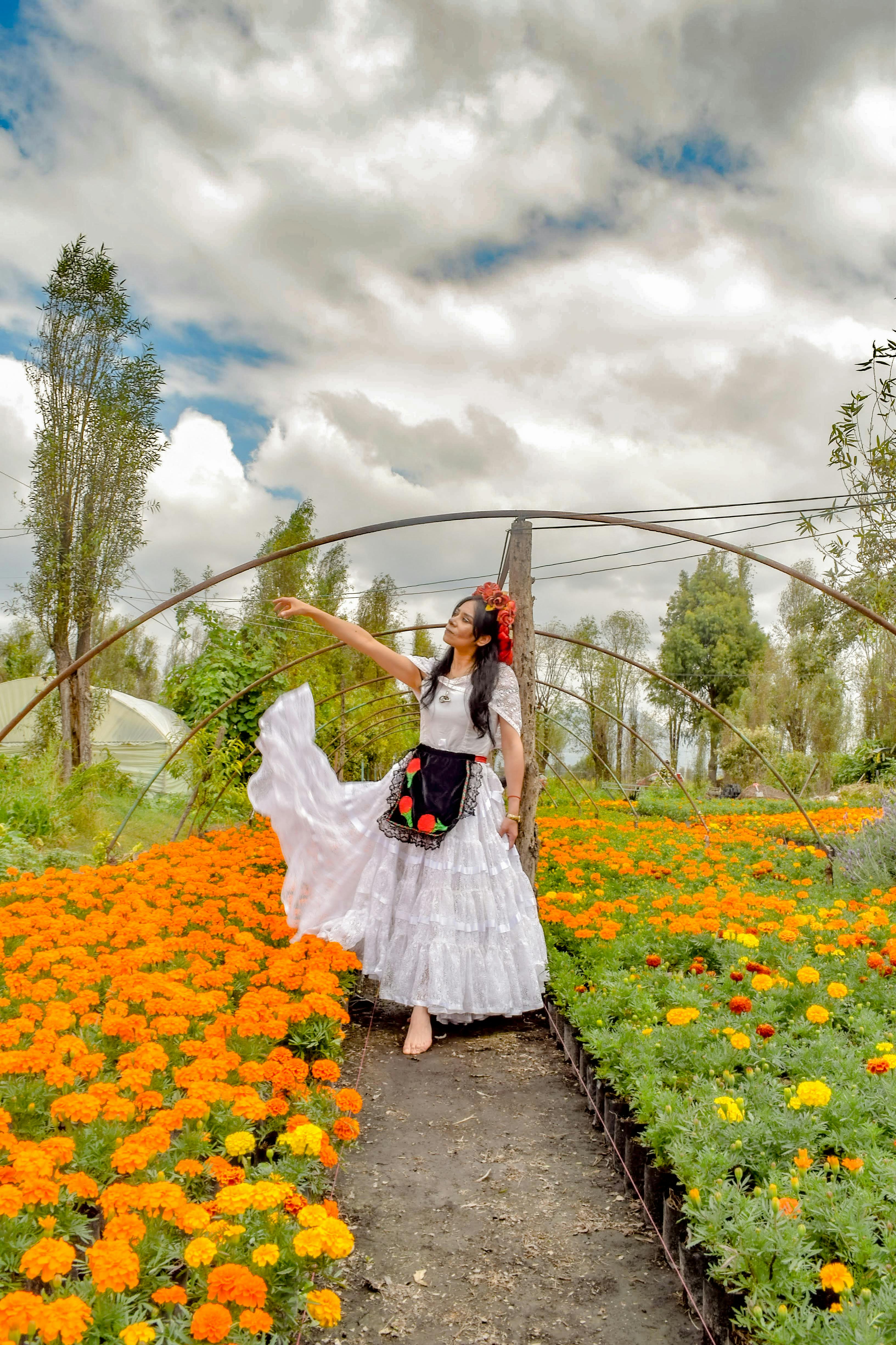 a young woman posing in white dress standing on a flower field