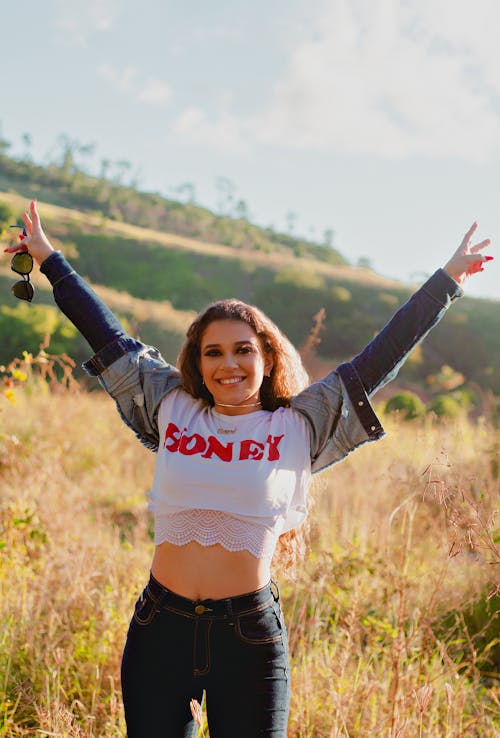 Woman in Crop Top and Denim Jacket Standing on Grass Field
