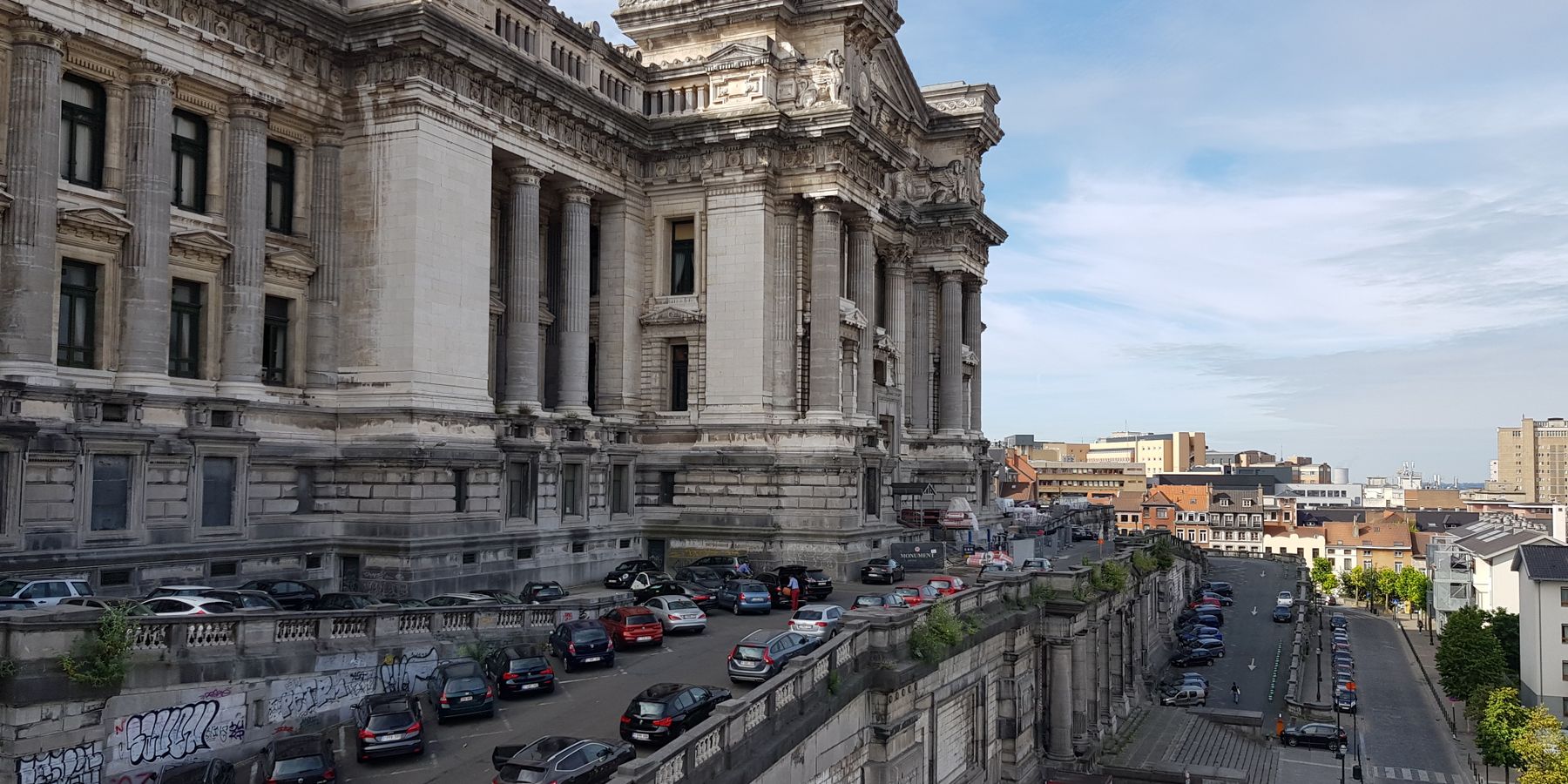 View of Brussels' iconic Palais de Justice with parked cars and urban landscape.