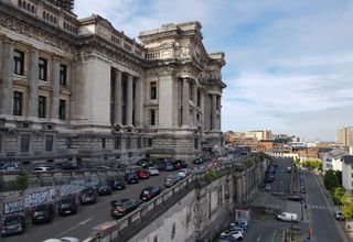 View of Brussels' iconic Palais de Justice with parked cars and urban landscape.