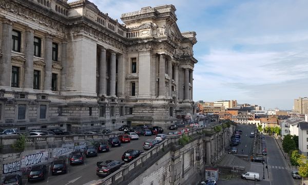 View of Brussels' iconic Palais de Justice with parked cars and urban landscape.