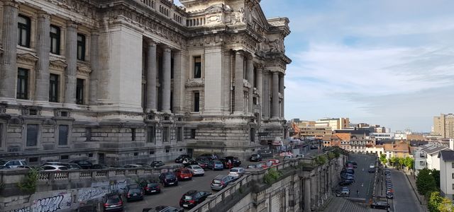 View of Brussels' iconic Palais de Justice with parked cars and urban landscape.