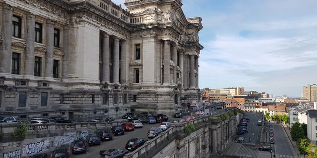 View of Brussels' iconic Palais de Justice with parked cars and urban landscape.