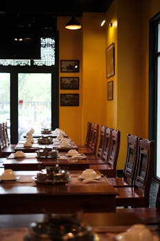 Luxurious dining room featuring elegant wooden furniture and neatly arranged tableware in a warm setting.