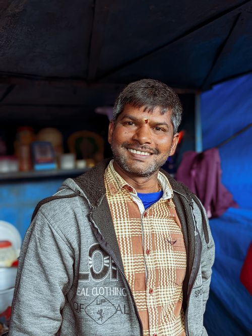 Free Portrait of a smiling man wearing a plaid shirt and gray jacket inside a cozy setting. Stock Photo