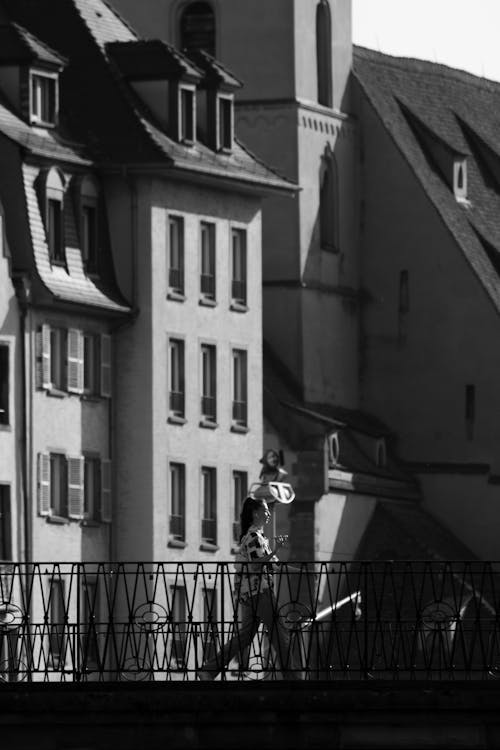 Candid Photo of a Woman Walking on a Bridge on the Background of Residential Buildings in City 