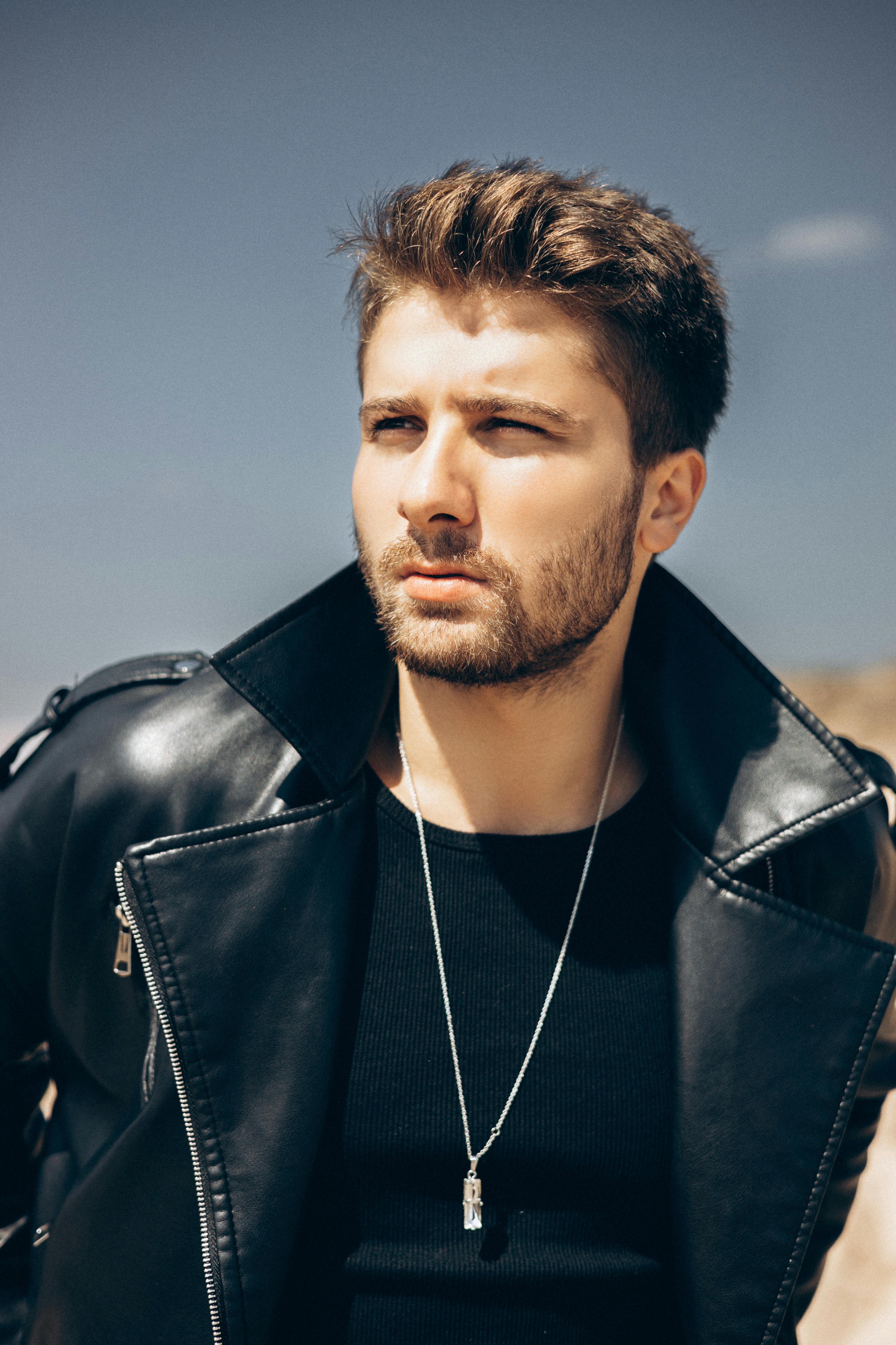 Portrait of a stylish man in a black leather jacket and necklace, outdoors in Turkey.