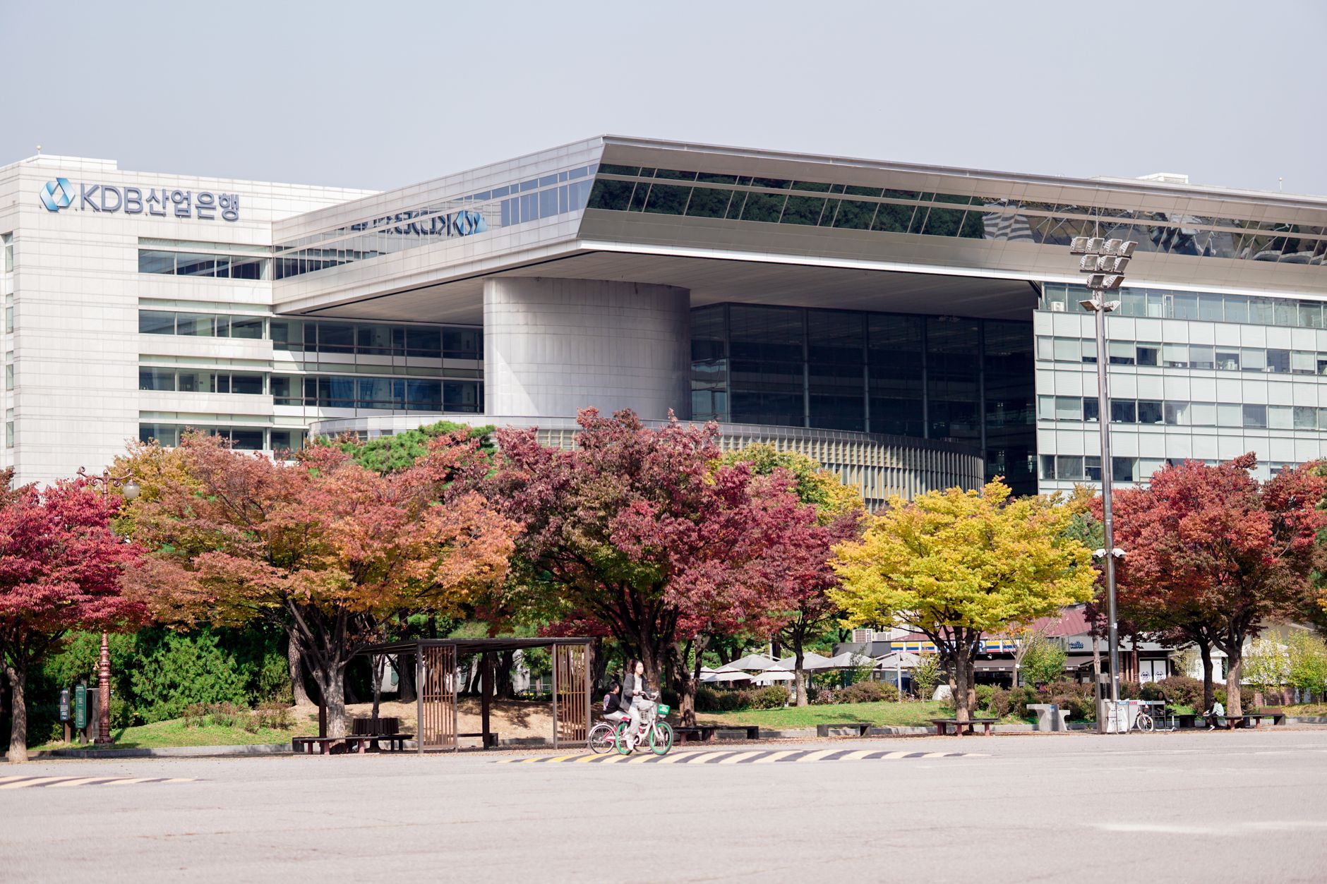 A modern urban building surrounded by colorful autumn trees in a cityscape setting.